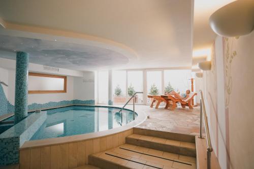 una piscina en un hotel con gente sentada en sillas en Olimpionico Hotel en Castello di Fiemme