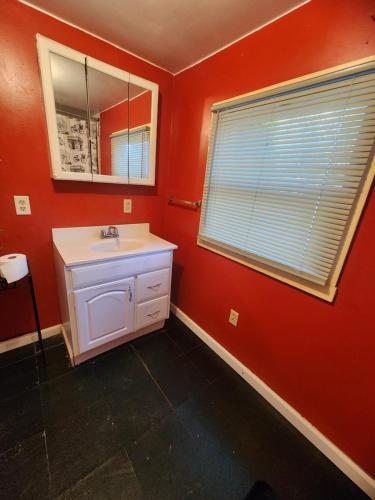 ein Bad mit roten Wänden, einem Waschbecken und einem Fenster in der Unterkunft Westfield's choice in Westfield