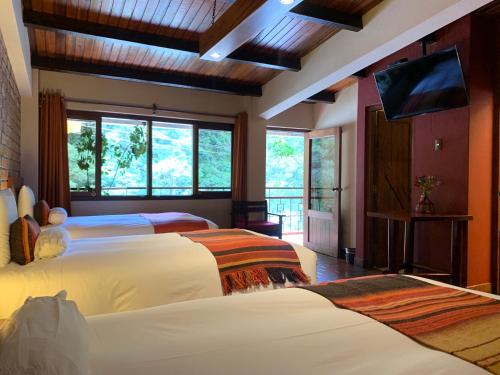 a bedroom with two beds and a flat screen tv at Panorama B&B in Machu Picchu