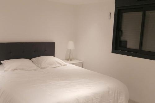 a white bed in a white room with a window at Superbe appartement JO 2024 in Plaisir