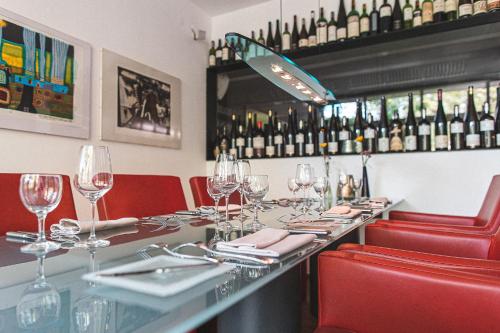 a restaurant with a long table with red chairs and wine bottles at Mühle am Schlossberg in Wartenberg-Rohrbach