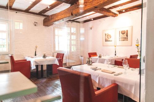 a restaurant with white tables and red chairs at Mühle am Schlossberg in Wartenberg-Rohrbach