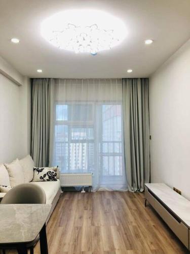 ein Wohnzimmer mit einem Sofa und einem großen Fenster in der Unterkunft Selbe Apartment "USA Embassy proximity" in Ulaanbaatar
