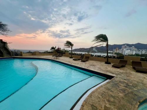 una piscina con sedie e palme in un edificio di Edificio el Peñón del Rodadero Apto 1102 B a Santa Marta