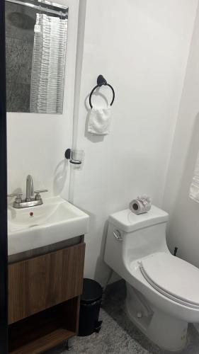 a white bathroom with a toilet and a sink at HOTEL and Suites Cananea in Cananea