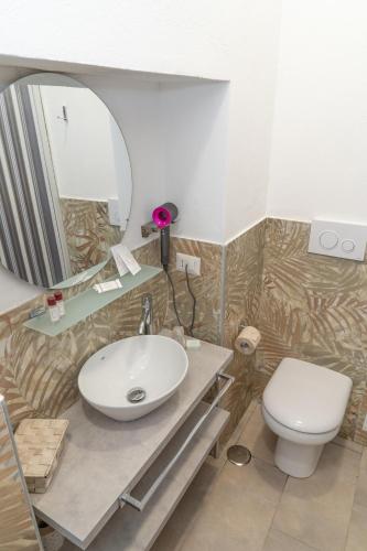 a bathroom with a sink and a toilet and a mirror at THE SUN HOTEL BOUTIQUE NAPOLI in Naples