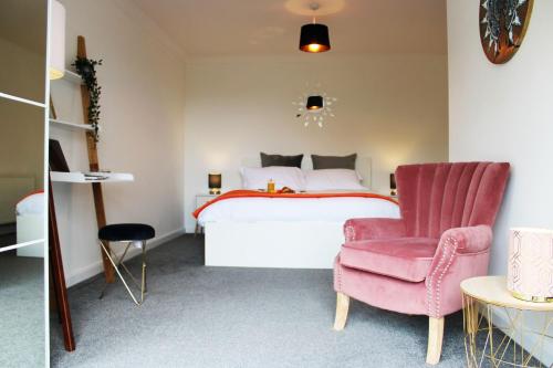 een slaapkamer met een bed en een roze stoel bij Ely Elegance in Ely