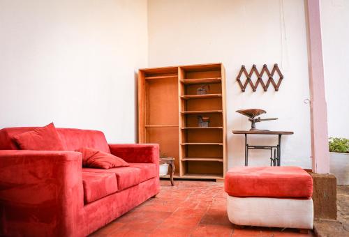 a living room with a red couch and a stool at Aura Hotel Parque Barichara By Infinity in Barichara