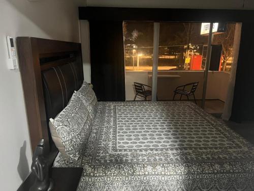 a bedroom with a bed and a window with chairs at HOTEL and Suites Cananea in Cananea