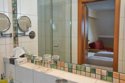 a bathroom with a mirror and a sink at Hotel Römer by Fairway Hotels in Günzburg