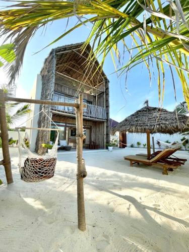 a resort with a hammock on the beach at Mfumbwi Twins Villa in Jambiani