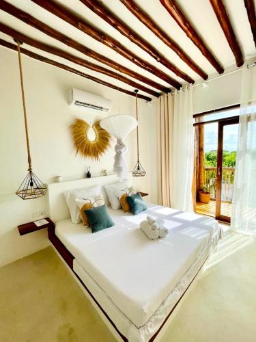a bedroom with a large white bed with a window at Mfumbwi Twins Villa in Jambiani