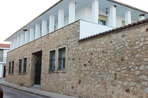 um edifício com janelas e uma parede de pedra em Casa Rural Las Parras 48 em Malpartida de Cáceres