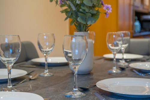 a table with wine glasses and plates and a vase with flowers at Stylish & spacious 3 bedroom entire house in Lisburn with parking in Lisburn