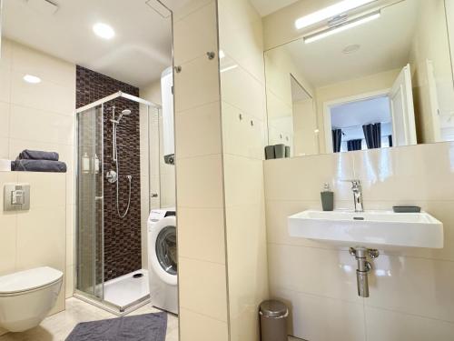 uma casa de banho com um lavatório e uma máquina de lavar roupa em New modern-style apartment with balcony in the Prague 2 em Praga