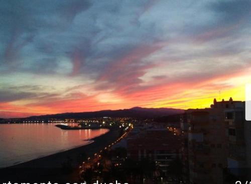 a sunset over a city with a body of water at Casa Rosa in Algarrobo-Costa