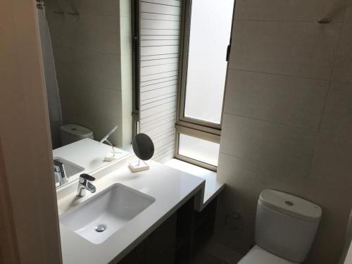 baño con lavabo y aseo y ventana en Kennedy Premium Apartments II, en Santiago