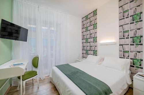 a bedroom with a bed and a desk and a television at Residenze Asproni Serviced Apartments in Cagliari