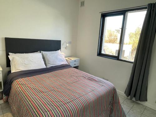 a bedroom with a bed with a striped comforter and a window at Hermoso departamento panorámico en Rio Gallegos in Río Gallegos