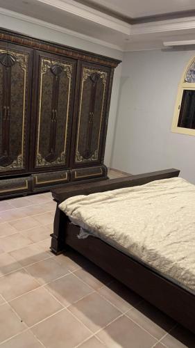 a bedroom with a bed and a wooden cabinet at شقة فندقية in Al Madinah