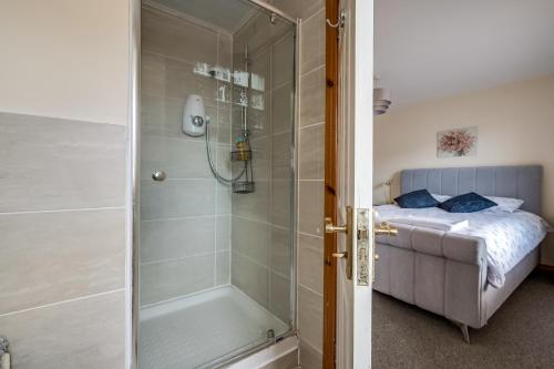 a shower with a glass door next to a bed at Stylish & spacious 3 bedroom entire house in Lisburn with parking in Lisburn