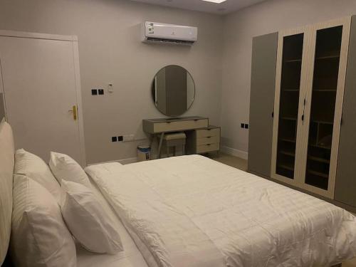a bedroom with a large bed and a mirror at شقة مريحة بتصميم انيق ودخول ذكي in Riyadh