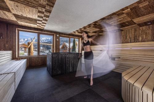 a woman is standing in a sauna at Hotel Ravelli Luxury Spa in Mezzana