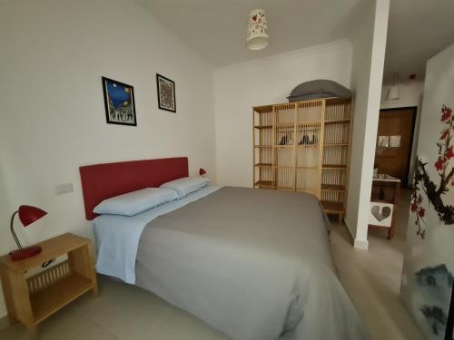 Schlafzimmer mit einem großen weißen Bett mit einem roten Kopfteil in der Unterkunft Cozy studio flat in Rome in Rom