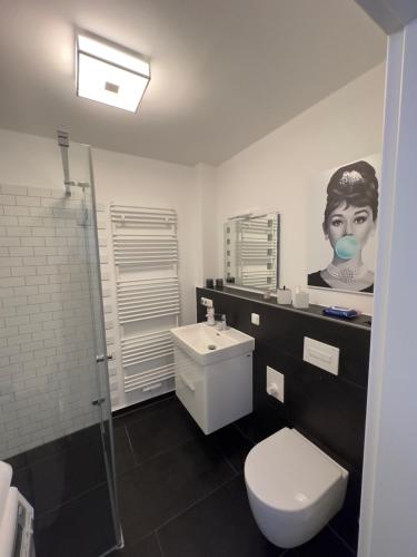 un baño con aseo y una foto de una mujer en Business-Apartment, en Leipzig