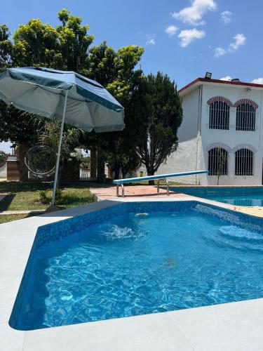 a blue swimming pool with an umbrella and a table at Quinta Rinos in Los Limones