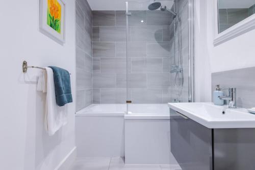 a white bathroom with a shower and a sink at Number 21: A Breathtaking Chester Cottage with Parking in Mollington