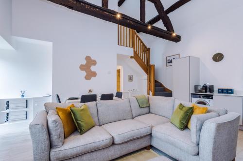 a living room with a gray couch with yellow pillows at Number 21: A Breathtaking Chester Cottage with Parking in Mollington