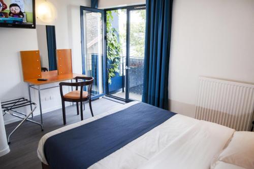 um quarto com uma cama, uma secretária e uma janela em Solar Hotel em Paris