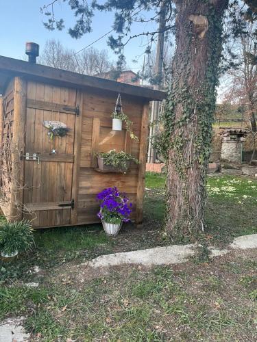 a wooden shed with flowers and a tree at La Casina di Sandro in Nocera Umbra