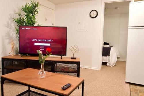 a living room with a television and a vase of flowers on a table at NEW Gorgeous Space in Moose Jaw Coffee Parking 4k Smart TV in Moose Jaw