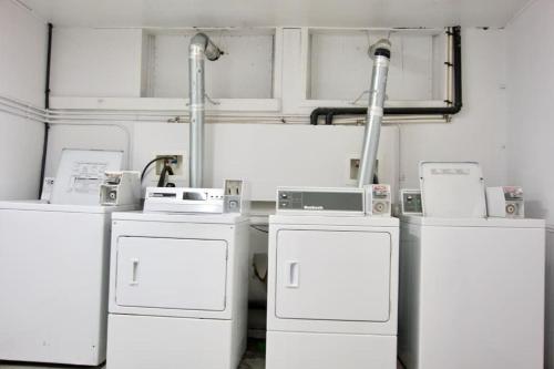 a room with three washers and machines in it at NEW Gorgeous Space in Moose Jaw Coffee Parking 4k Smart TV in Moose Jaw