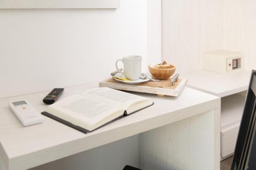 an open book on a table with a cup and a coffee mug at Hotel Hawaii Bed and Coffee in Riccione