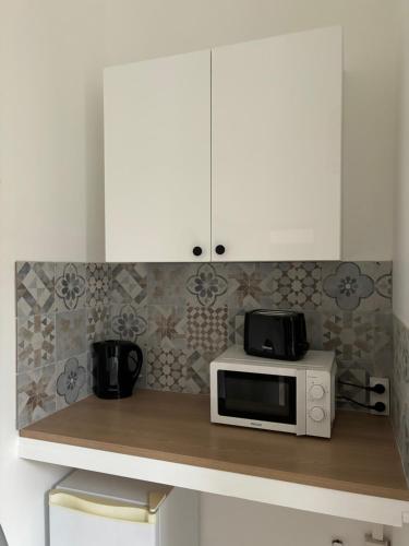 une cuisine avec des placards blancs et un four micro-ondes sur un comptoir dans l'établissement Beau studio rénové - centre-ville/université, au Havre