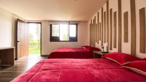 two beds in a room with red sheets at Hotel rio de piedras in Tuta