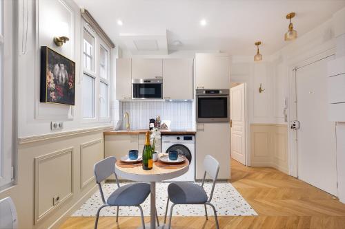 une cuisine blanche avec une table et des chaises dans l'établissement Montmartre 2 Pièces, à Paris
