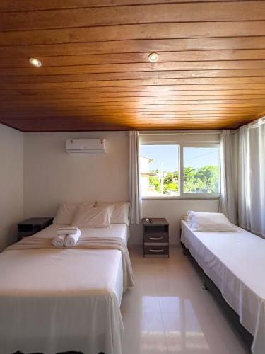 two beds in a room with a wooden ceiling at Pousada Linda Flor in Morro de São Paulo