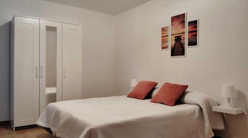 a white bedroom with a bed with two red pillows at Amplio apartamento recién reformado in Tejina