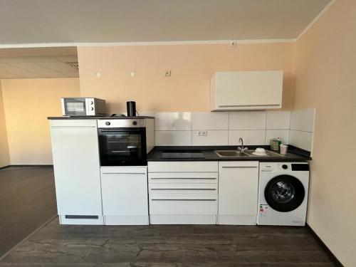 a kitchen with white cabinets and a washing machine at Eterna Comfort Living in Essen