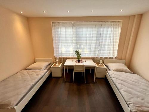 エッセンにあるEterna Comfort Livingのベッド2台、テーブル、窓が備わる客室です。