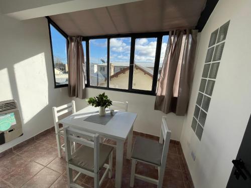 a dining room with a table and chairs and windows at Hermoso departamento panorámico en Rio Gallegos in Río Gallegos