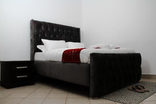 a bed with a black headboard and white sheets at Springfield Luxury Homes in Kuywa