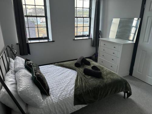 a bedroom with a bed and a dresser and windows at The Lowther Penthouse - 2 Bedrooms - Sleeps 4 in Whitehaven