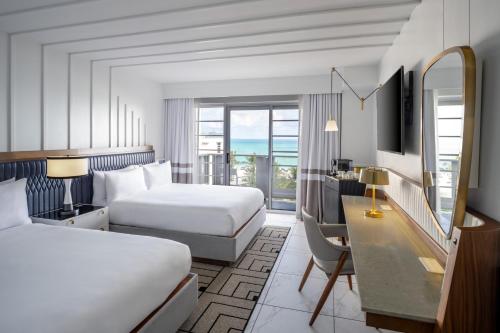 a hotel room with two beds and a desk at Cadillac Hotel & Beach Club, Autograph Collection in Miami Beach