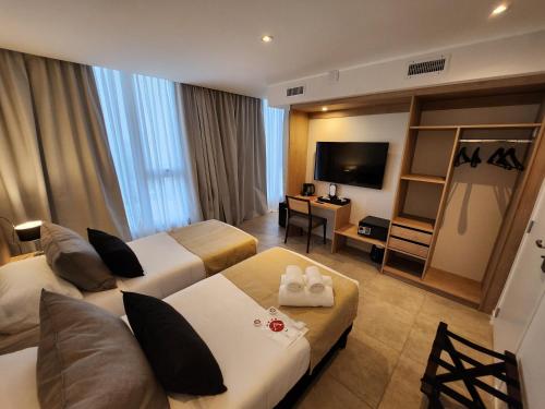 a hotel room with two beds and a television at Amerian Rio Cuarto Apart & Suites in Río Cuarto