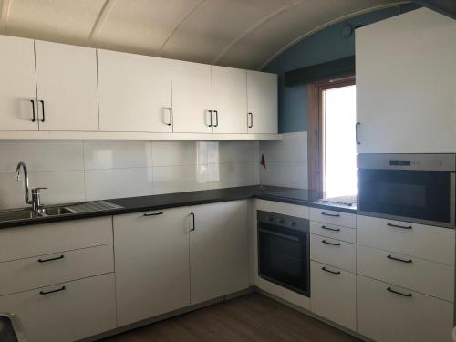 an empty kitchen with white cabinets and a window at Rena Hostel in Rena